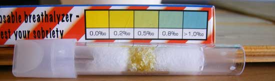 breathaliser after being used, held up next to the colour chart